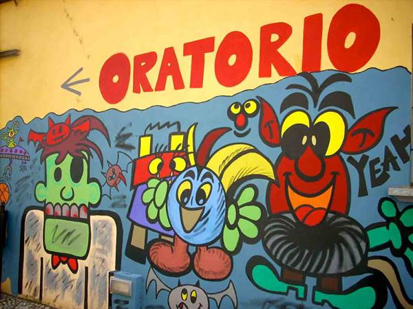 Colorful mural with cartoon monsters and red Oratorio sign on yellow wall