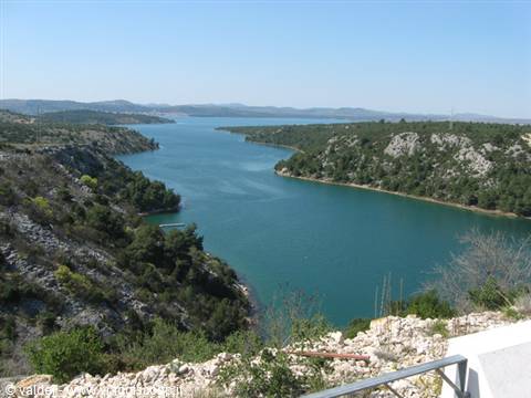 turquoise waters of the Krka estuary between rocky hills and Mediterranean shrubs