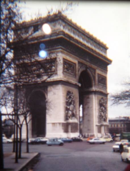 Arc de Triomphe in Paris, carved stone, vintage cars, bare trees, grey light