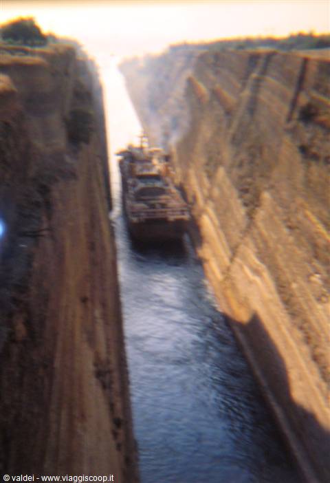 Ship crossing the Corinth Canal between steep rock walls in morning light
