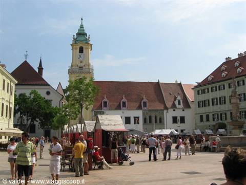 Tourists among colorful market stalls on Bratislava main square with Old Town Hall tower
