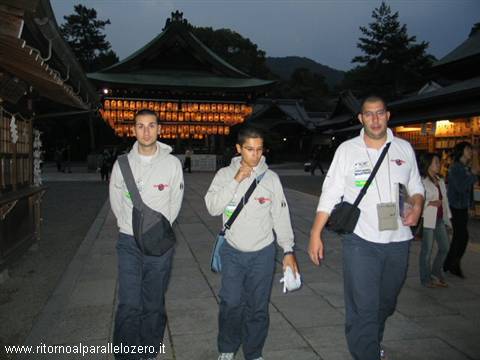 Three young men walking at Yasaka Shrine in Kyoto among lit lanterns