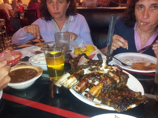 Two women eating BBQ ribs at an American diner, beer and chili on the table