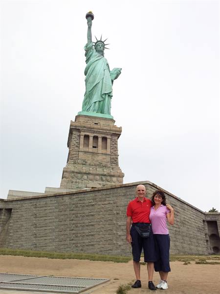 Tourist couple posing in front of the Statue of Liberty in New York