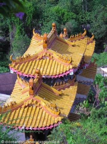 Pagoda roofs with yellow tiles and ornate ridges among green trees, Kek Lok Si