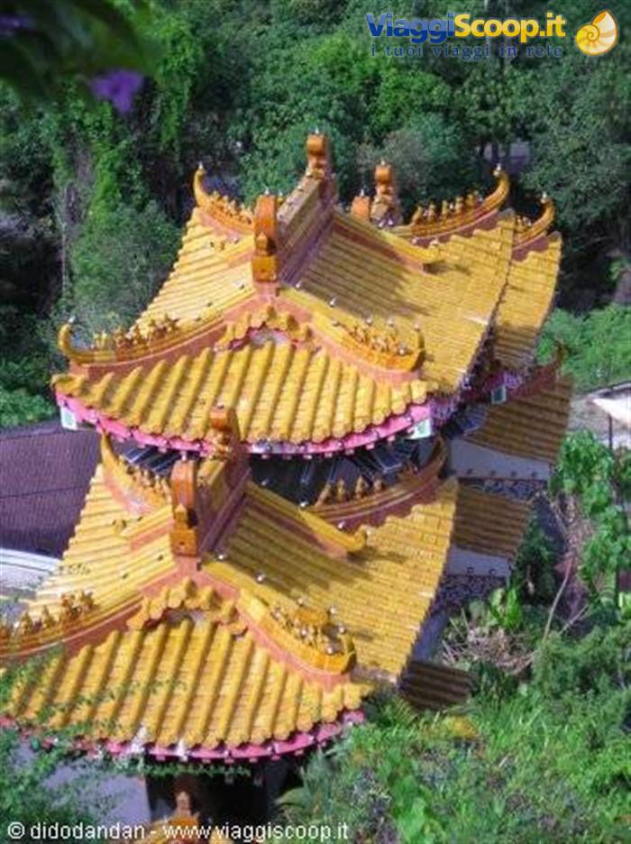 Pagoda roofs with yellow tiles and ornate ridges among green trees, Kek Lok Si