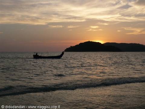 Fishing boat silhouette in front of an island at sunset