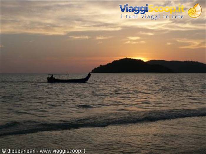 Fishing boat silhouette in front of an island at sunset