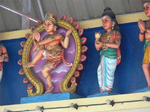 Painted Hindu deity statues on temple facade, dancing figure inside ornate arches