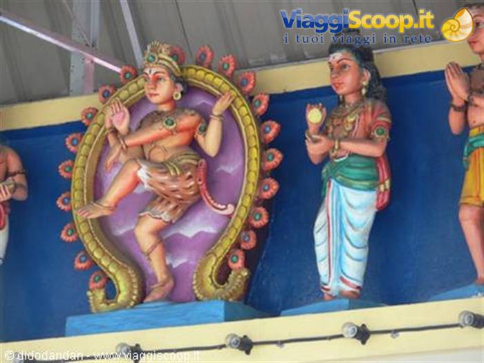 Painted Hindu deity statues on temple facade, dancing figure inside ornate arches
