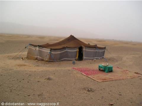 Berber tent in the desert with carpet and small table outside, hazy sky