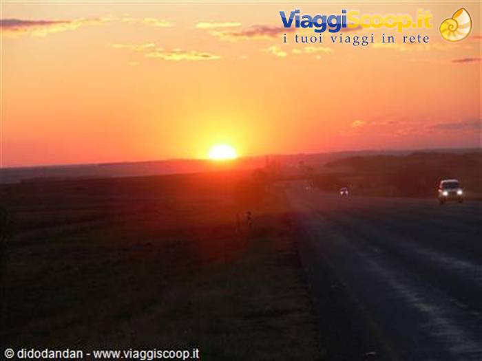 Low sun glowing orange over the highway, cars driving with headlights on