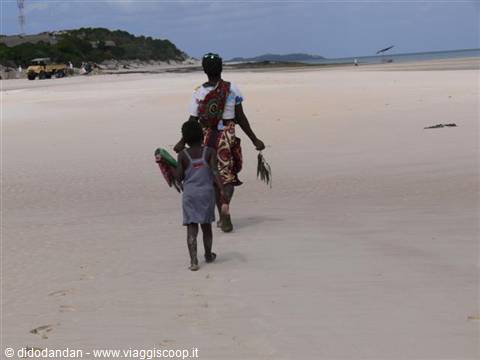 Woman and child walking barefoot on the sand toward the sea, Vilanculos