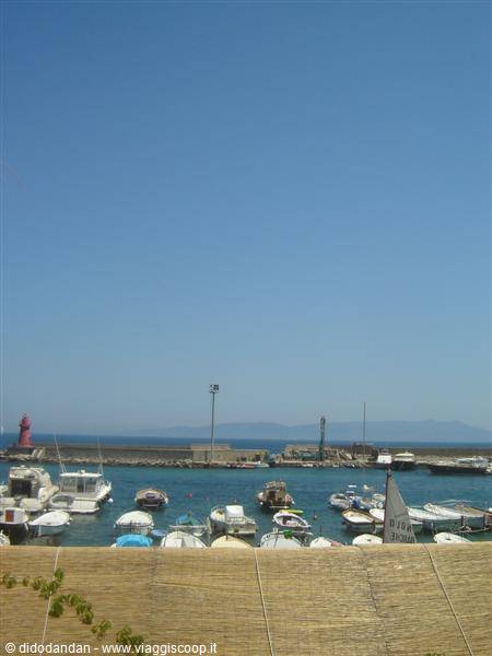Red lighthouse and moored boats in the harbor under blue sky