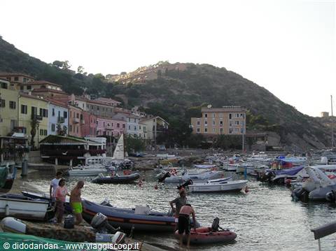 Boats moored at Giglio harbor, colorful houses on the hillside