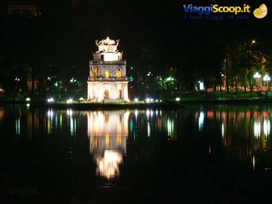 Turtle Tower lit up at night on Hoan Kiem Lake, reflected in the water
