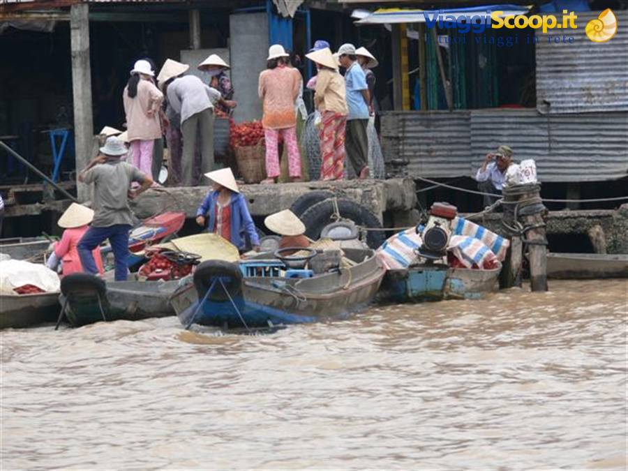 Floating market: boats loaded with fruit and conical-hat vendors on muddy river