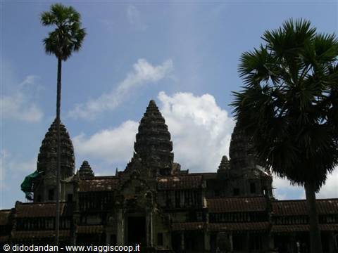 Stone towers of Angkor Wat rise behind palms and clouds