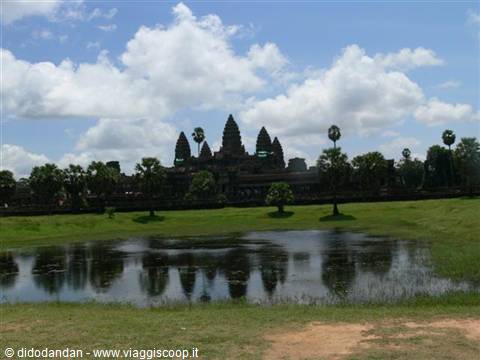 Angkor Wat towers reflect in a pond among palm trees and green lawns