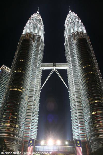 The illuminated Petronas Towers at night in Kuala Lumpur, with Malaysian flags