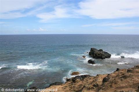 Blue ocean with dark volcanic rocks and breaking white waves
