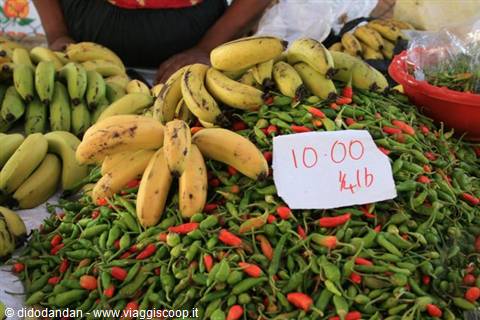 Bananas and green chili peppers piled at a market stall, price sign