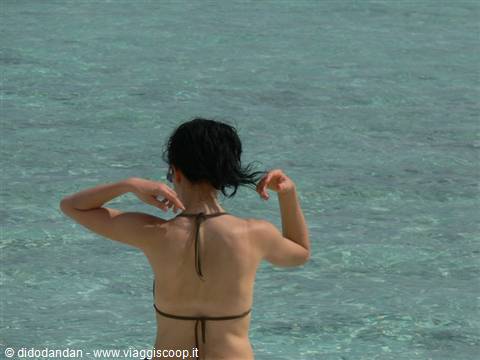 Woman in bikini fixing her hair in clear turquoise water