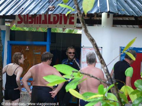 Tourists in swimwear at the Sub Maldives dive center framed by green leaves