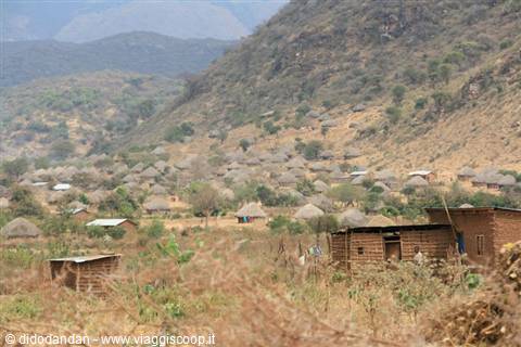 Village with thatched huts and brick houses at the foot of the hill