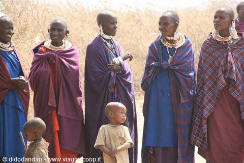 Maasai women wearing beaded jewelry with children, dry bushland