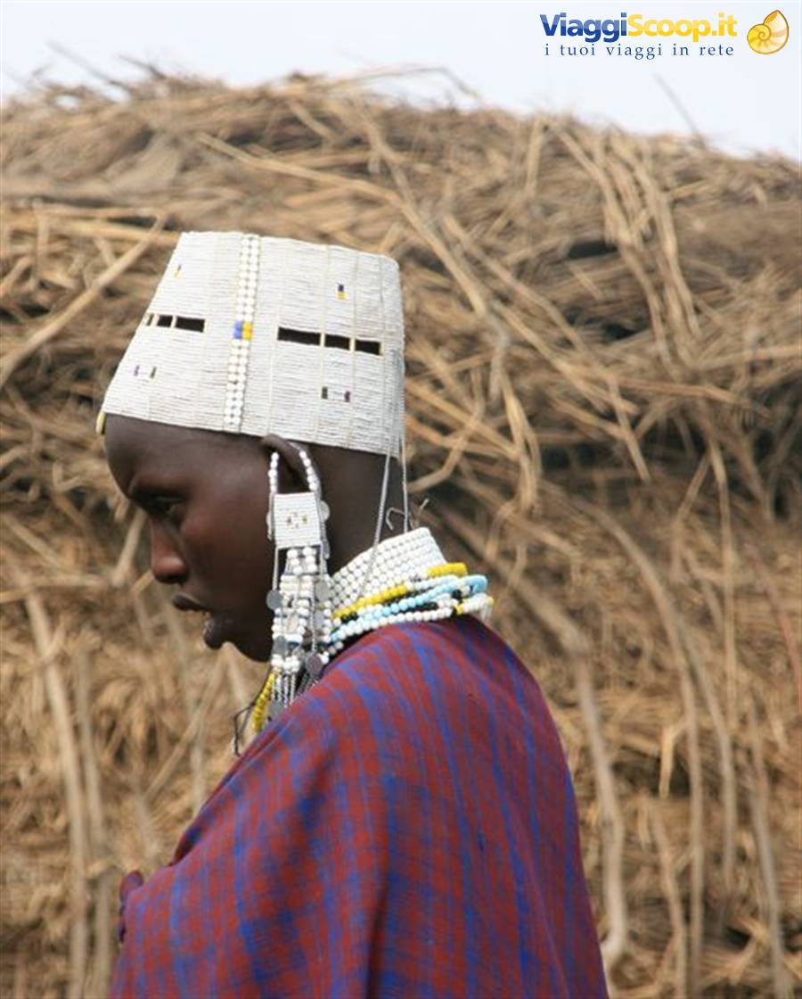Maasai man wearing white beaded headdress and earrings in front of straw mats