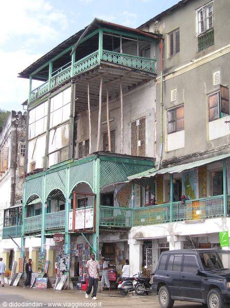 Colonial building with green iron balconies and shops along the busy street