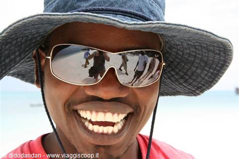 Smiling man wearing blue hat and mirrored sunglasses on the beach