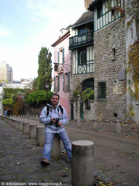 Tourist with camera sitting on a stone bollard in Montmartre