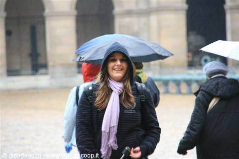 Smiling woman under umbrella in the rain at the Louvre courtyard