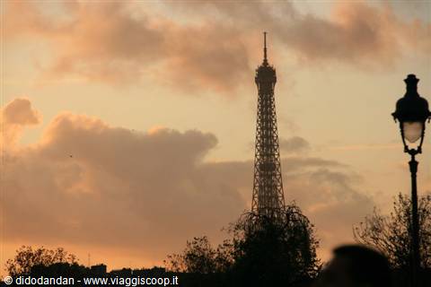 The Eiffel Tower silhouetted against pink clouds beside a lamppost