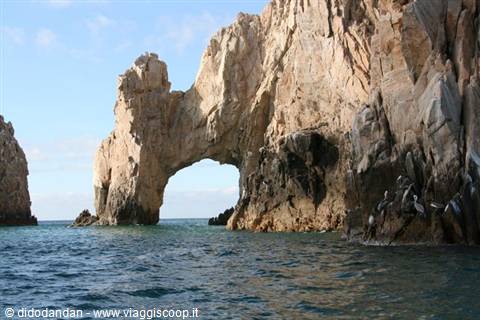 The rock arch of Cabo San Lucas rises over the blue water