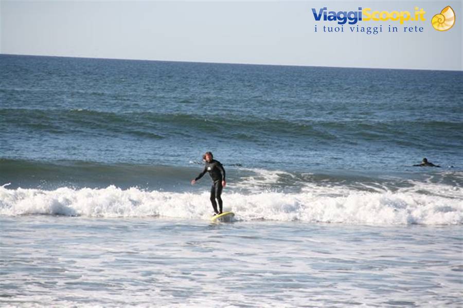 Surfer in black wetsuit on yellow board riding a wave