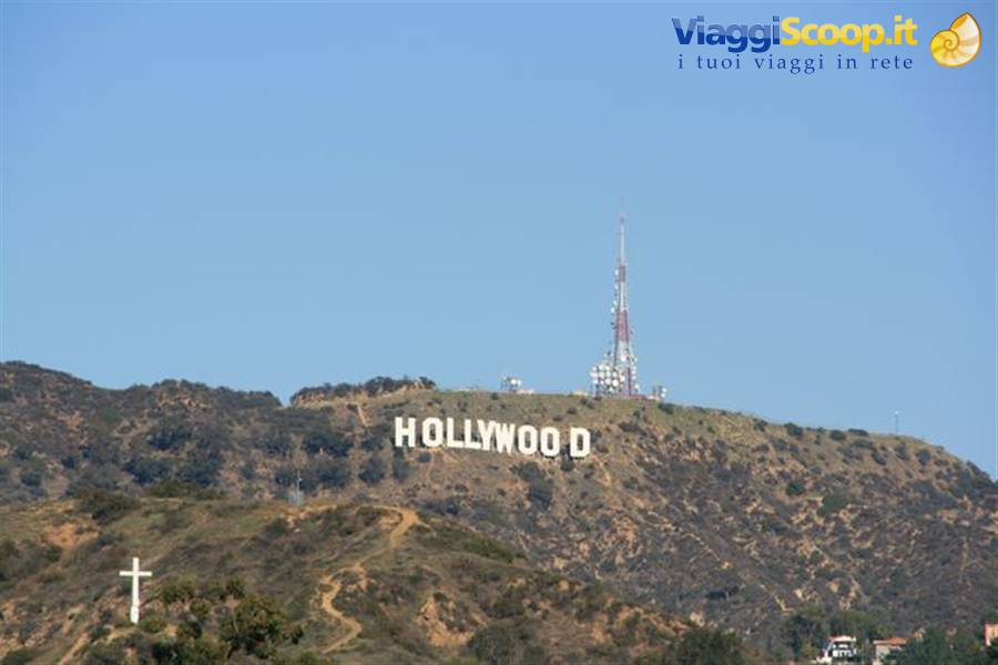 White Hollywood sign on dry hillside, radio antenna, blue sky