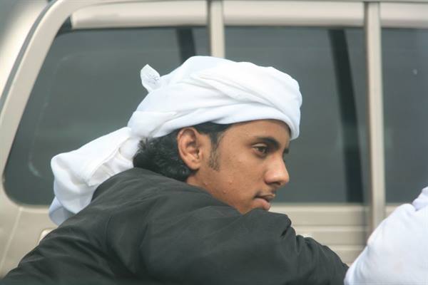 Young man in white turban beside a van, soft daylight