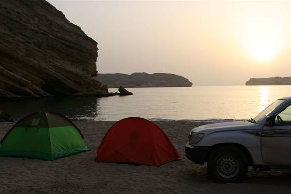 two camping tents and an SUV on the beach at sunrise