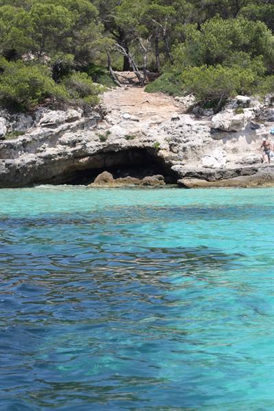 Rocky cave beneath pines, crystal clear turquoise sea, Cala Macarella