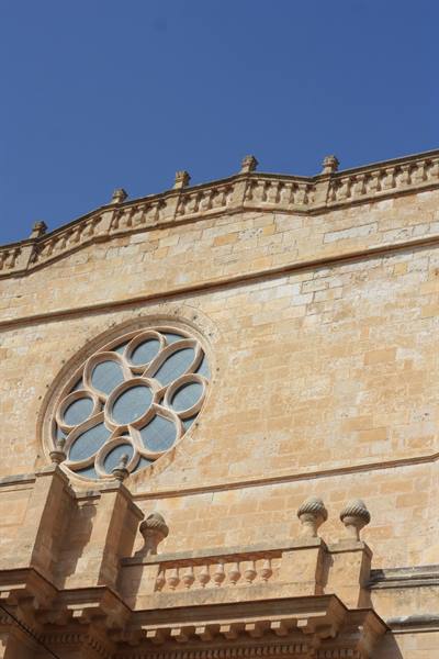 Stone rose window on a cathedral facade, blue sky, sunlight