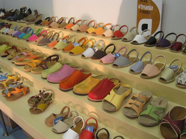 Wooden shelves displaying colorful handmade sandals in a shop, Artesania sign