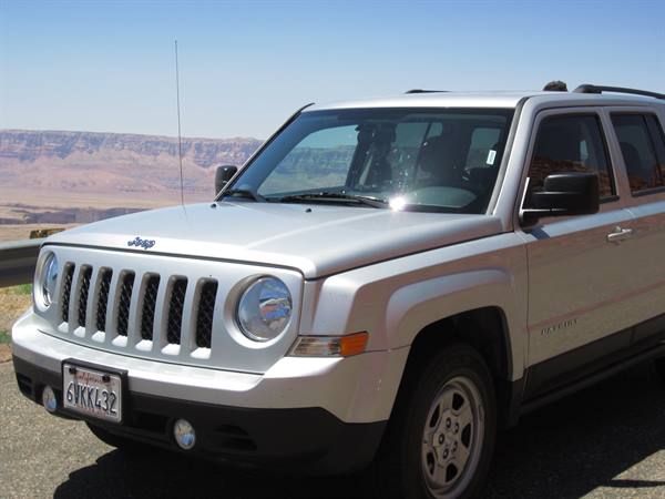 Silver Jeep Patriot parked with colorful canyon behind