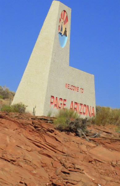 Concrete Welcome to Page Arizona sign among red rocks under blue sky
