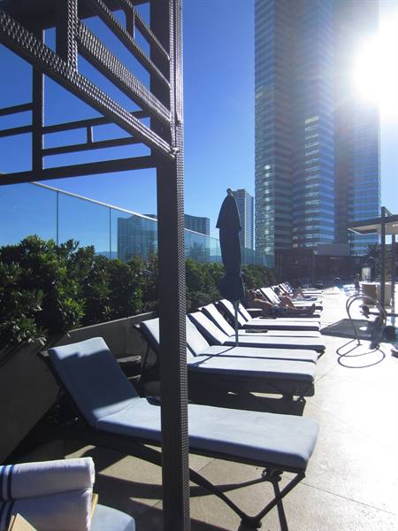 Poolside loungers on a terrace, mirrored skyscrapers gleaming under the sun
