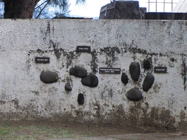 Black stones and plaques mark flood levels on a weathered wall