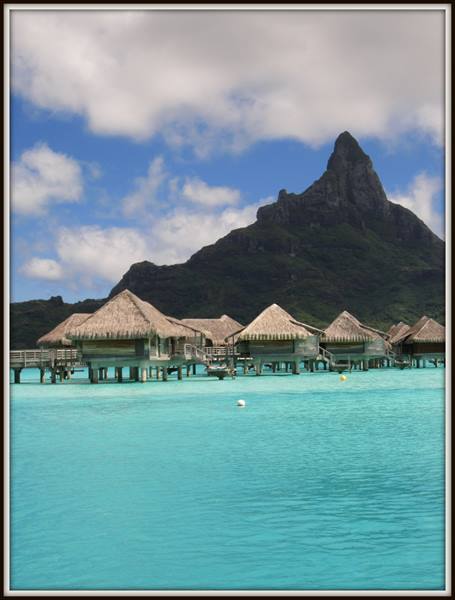 Overwater thatched bungalows on turquoise lagoon beneath Mount Otemanu, Bora Bora