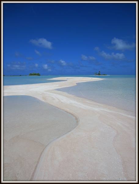 White sandbar winding between turquoise shallows, green islets on the horizon